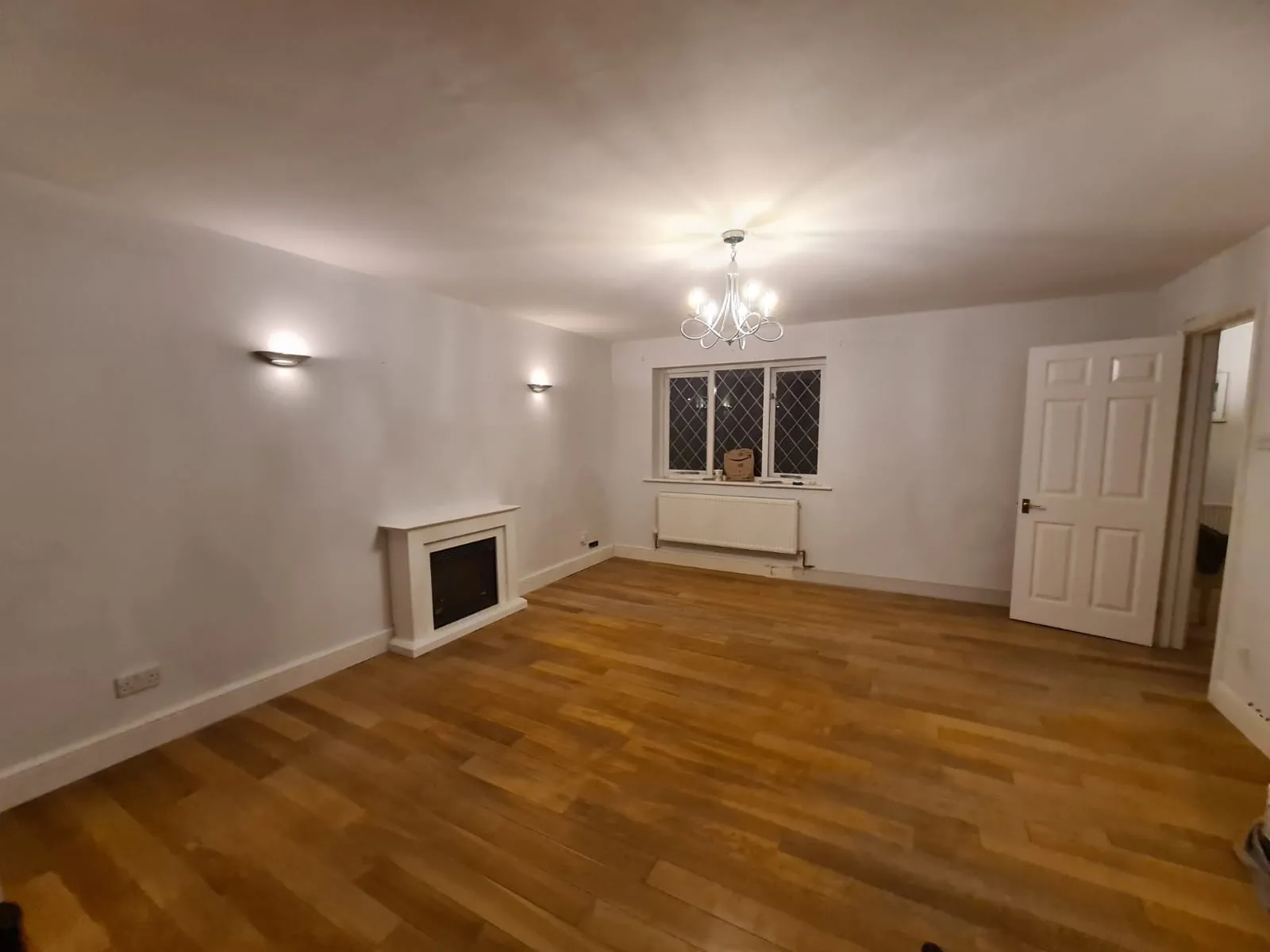 wooden floor with fireplace and chandelier